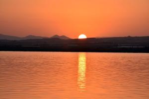 a sunset over a body of water with the sun setting at Casa Alex Torrevieja- Holiday House - con piscina comunitaria in Torrevieja
