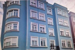 een blauw gebouw met witte ramen bij Alojamiento céntrico con encanto in Ferrol