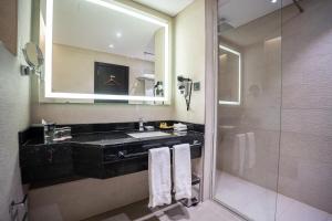 a bathroom with a sink and a mirror and a shower at Grand Millennium Al Seef Basra in Al Başrah