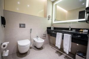 a bathroom with a toilet and a sink and a mirror at Grand Millennium Al Seef Basra in Al Başrah