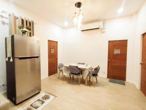 a kitchen with a table and a stainless steel refrigerator at คานาโฮมฮัก หนองกุง in Ban Tao No