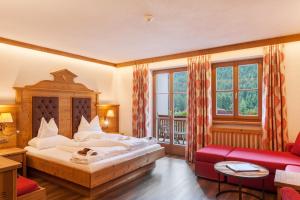 um quarto com uma cama grande e um sofá vermelho em Alphotel Tyrol em Racines