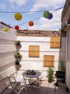 d'une terrasse avec une table, des chaises et des lanternes colorées. dans l'établissement Le Chat d'Or - 35m2 - Terrasse - BBQ - WIFI HD, à Amiens