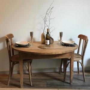 a wooden table with two chairs and a bottle of wine at Appartement douillet, plein centre in Le Chambon-sur-Lignon