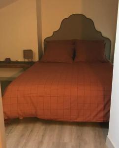 a bed with an orange comforter in a room at Appartement douillet, plein centre in Le Chambon-sur-Lignon +6 photos