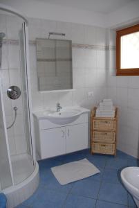 een witte badkamer met een wastafel en een douche bij Ansitz Weissenheim in Appiano sulla Strada del Vino