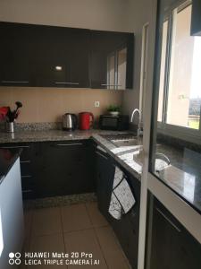 eine Küche mit schwarzen Schränken und einem Waschbecken in der Unterkunft Luxus Home in Oujda