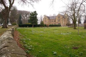 un mur en pierre devant une grande maison dans l'établissement Pentrehobyn Hall, à Wrexham