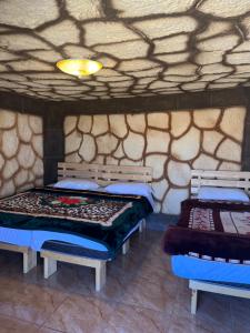 2 Betten in einem Zimmer mit einer Steinmauer in der Unterkunft Al-Nawatef ECO camp- Dana Nature Reserve in Dana