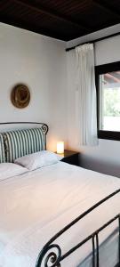 a white bedroom with a bed and a window at Trikorfo Bungalows in Gerakini