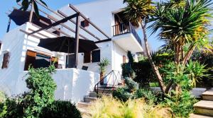 a white house with stairs and an umbrella at Trikorfo Bungalows in Gerakini