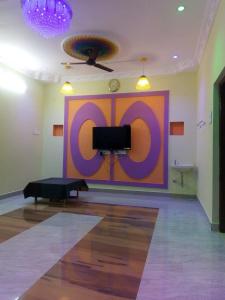Habitación con una gran pared púrpura y TV. en ECO VILLA, en Pondicherry