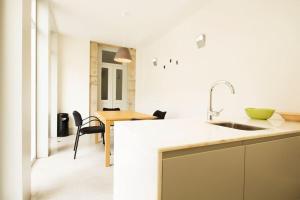 uma cozinha branca com um lavatório e uma mesa em OHH - Santo Ildefonso flat no Porto