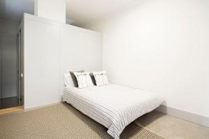 um quarto branco com uma cama numa parede branca em OHH - Santo Ildefonso flat no Porto