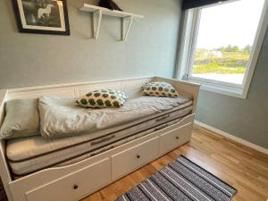 łóżko z poduszkami w pokoju z oknem w obiekcie Holiday home Hellesøy w mieście Bøvågen