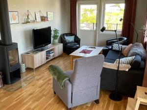 salon z kanapą, telewizorem i krzesłem w obiekcie Holiday home Hellesøy w mieście Bøvågen