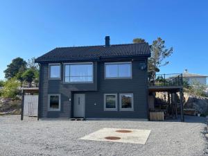 una casa negra sentada encima de un lote de grava en Holiday home Hellesøy, en Bøvågen