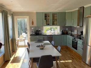 una cocina con armarios verdes y una mesa con sillas en Holiday home Hellesøy, en Bøvågen