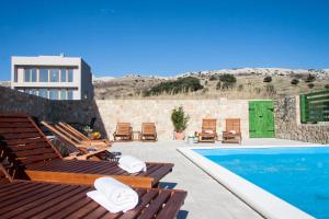 a pool with chaise lounge chairs and a swimming pool at Apartments Belveder in Pag