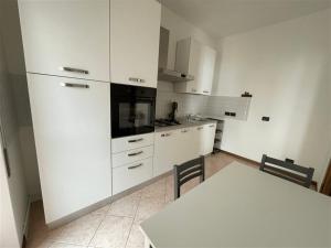 a kitchen with white cabinets and a table with chairs at Fabula Home Rental - Casa Pluto in Lovere