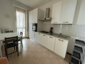 una cocina con armarios blancos, una mesa y una barra en Fabula Home Rental - Casa Pluto en Lovere