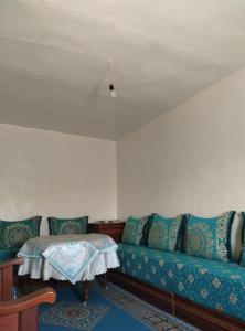 uma sala de estar com um sofá azul e uma mesa em شفشاون em Chefchaouene