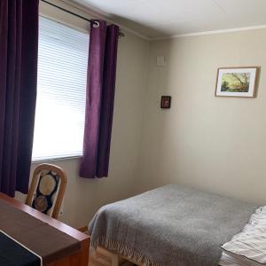 哈爾斯塔的住宿－Room in house on the road to Lofoten，一间卧室配有一张床和一个带紫色窗帘的窗户