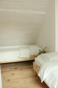 Montagnac-la-CrempseにあるLa bergerie des petits loupsの白い壁とウッドフロアの客室で、ベッド2台が備わります。