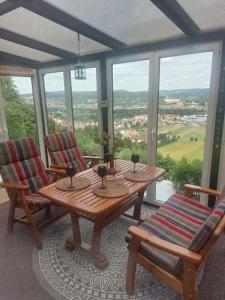 einen Tisch und Stühle in einem Zimmer mit Fenstern in der Unterkunft Bungalow mit Schlossblick in Rudolstadt