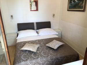 een bed in een kamer met twee kussens erop bij Apartmani Gloria in Brodarica