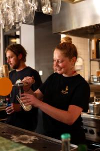 un hombre y una mujer en una cocina preparando comida en Hostel & Bar De Basis, en Zwolle