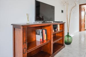 a wooden entertainment center with a television and books at Bright House, Pool & Workspace near Medano Beach in El Médano