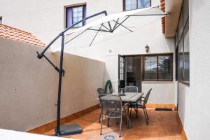 a white umbrella on a patio with a table and chairs at Bright House, Pool & Workspace near Medano Beach in El Médano