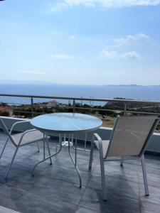a table and two chairs on a balcony with the ocean at 360° View Suites Sin in Neapoli Voion