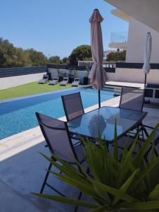 a glass table and chairs next to a swimming pool at Ca Na Xisca in Felanitx