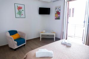 Un dormitorio con una cama y una silla y un televisor. en la terrazza di Rachele, en Castellammare del Golfo