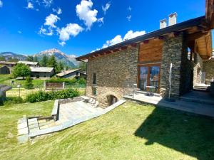 ein Steinhaus mit einer Terrasse und einem Hof in der Unterkunft Chalet Del Sole in Monfol