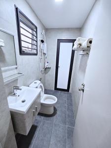 La salle de bains est pourvue d'un lavabo, de toilettes et d'une fenêtre. dans l'établissement Entire Home at Indahpura, Kulai, à Kulai