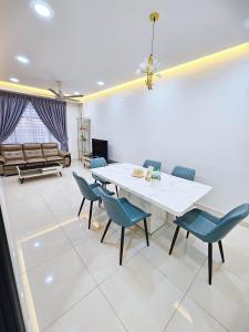Entire Home at Indahpura, Kulai في كولايْ: غرفة طعام مع طاولة بيضاء وكراسي زرقاء