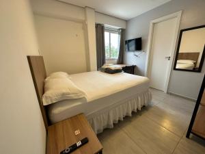 een slaapkamer met een groot bed en een spiegel bij WS SUÍTES HOTEL in Três Passos