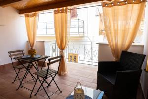 un soggiorno con tavolo, sedie e una grande finestra di la terrazza di Rachele a Castellammare del Golfo