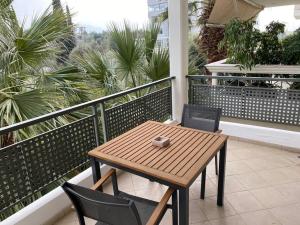 a wooden table and chairs on a balcony with palm trees at Cozy Apartment with Scenic View in Athens