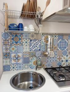cocina con fregadero, fogones y azulejos en Goccia del mare en Isola delle Femmine