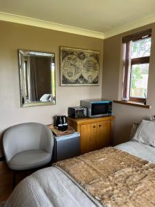 a bedroom with a bed and a chair and a microwave at Cherry blossom lodge in Marton