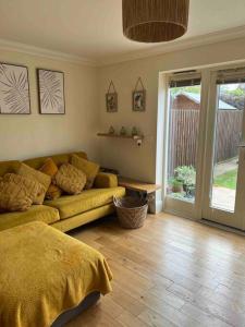 a living room with a yellow couch and a wooden floor at NEW! 3 bedroom. On-drive parking. Close to the A1 in Long Bennington