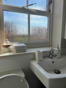 a bathroom with a window and a toilet and a sink at NEW! 3 bedroom. On-drive parking. Close to the A1 in Long Bennington