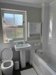 a bathroom with a toilet and a sink and a tub at NEW! 3 bedroom. On-drive parking. Close to the A1 in Long Bennington