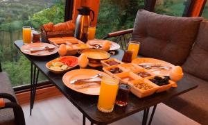 a breakfast table with food and orange juice on it at Necran Bungalow اكواخ ايدر in Rize