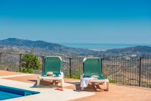 two green chairs sitting next to a swimming pool at Cantueso Holiday Park in Periana