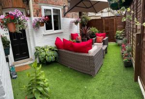 un patio con un sofá con almohadas rojas en la hierba en Self contained Garden Flat newly Refurbished, en Bridlington